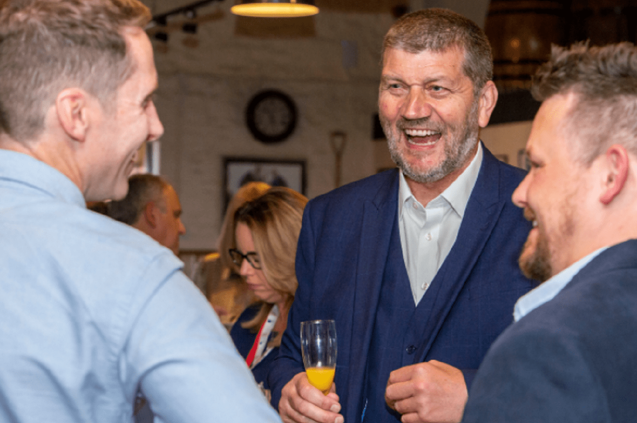 Staff members smiling as they raise a glass of fizz to toast the company’s 50th anniversary.