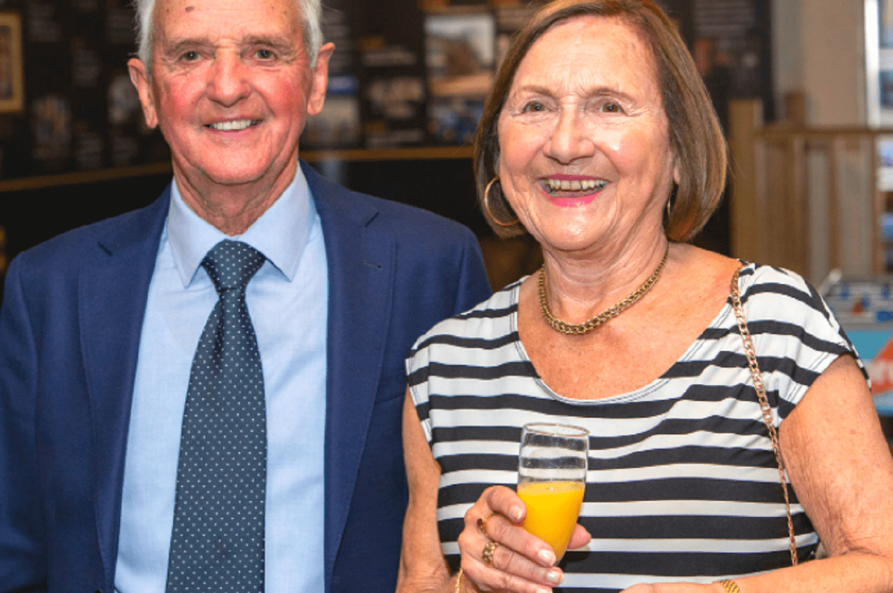 Staff members smiling as they raise a glass of fizz to toast the company’s 50th anniversary.