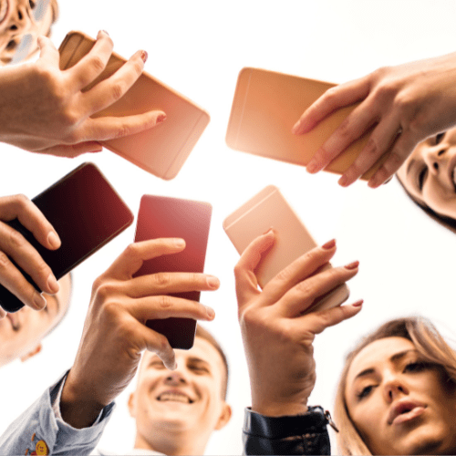 A group of people stood in circle looking down at their phones