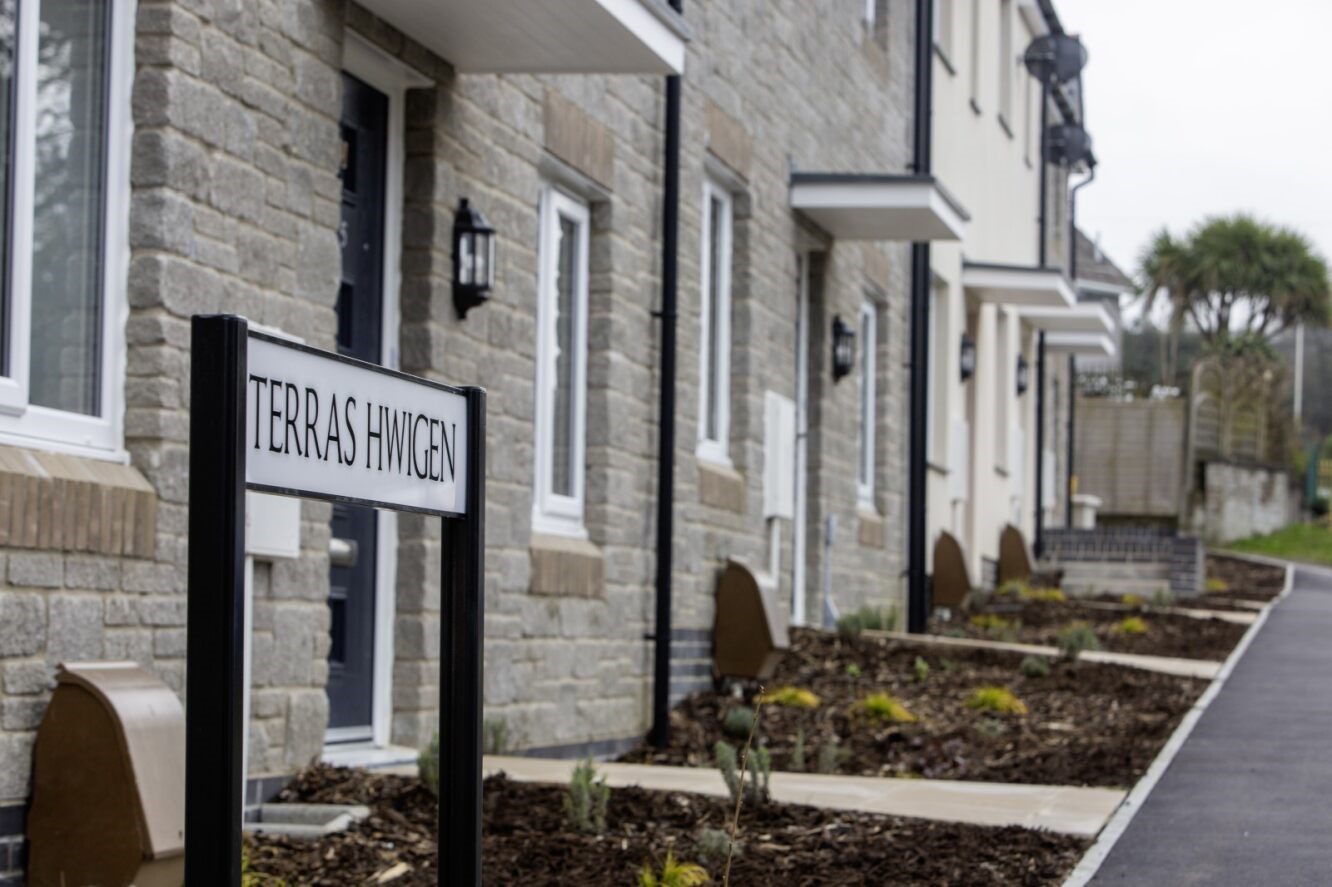 Close up photograph of a terrace of homes, with a street sign in the foreground saying Terras Hwigen.